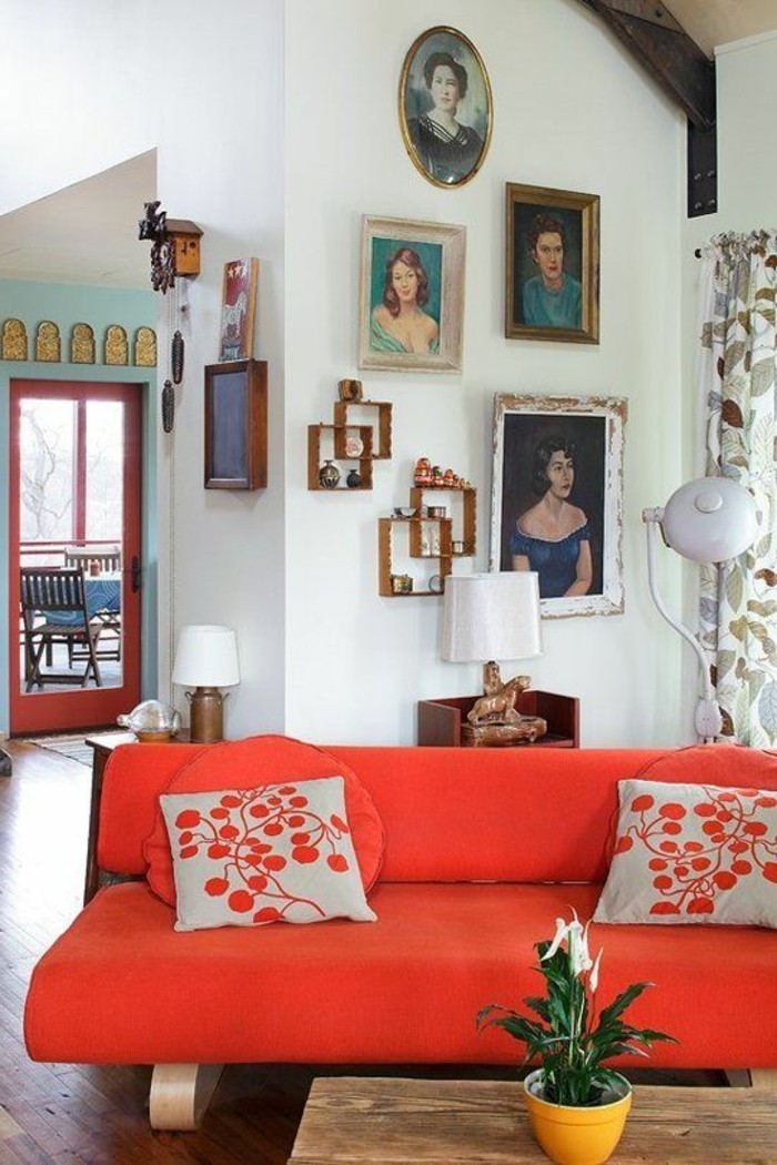 artistische-Wohnung-Portraits-an-der-Wand-kleine-rote-Couch-mit-modernem-Design