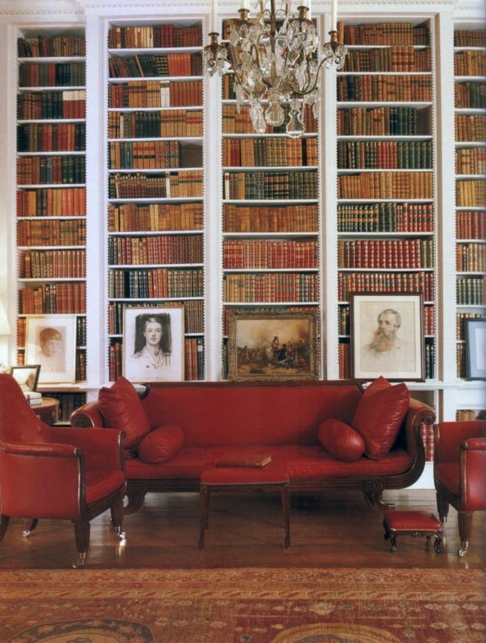 elegantes-Interieur-Bücherwand-Portraits-rote-Ledercouch-Sessel