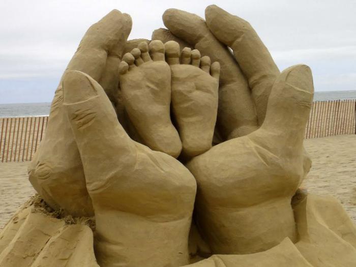 moderne-Skulptur-aus-Sand-Kinder-Füße-in-den-Händen-vom-Vater