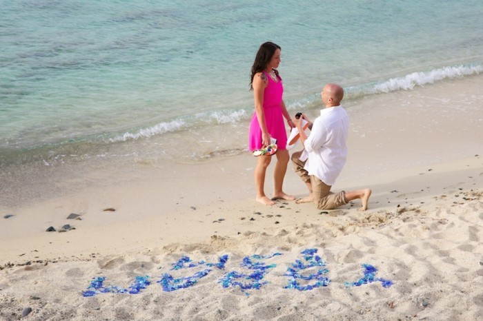 Romantischer-Heiratsantrag-am-Strand-mit-Buchstaben-auf-Sand