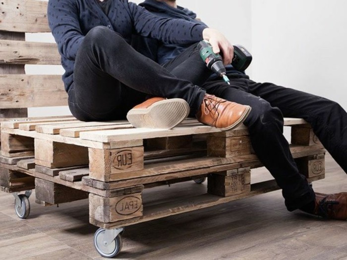 kreatives-modell-sofa-aus-europaletten-leute-sitzen-darauf-weißer-hintergrund