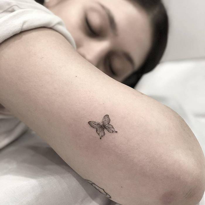 Kleines Schmetterling Tattoo am Oberarm, Mini Tattoo Ideen für Frauen, schlafendes Mädchen 