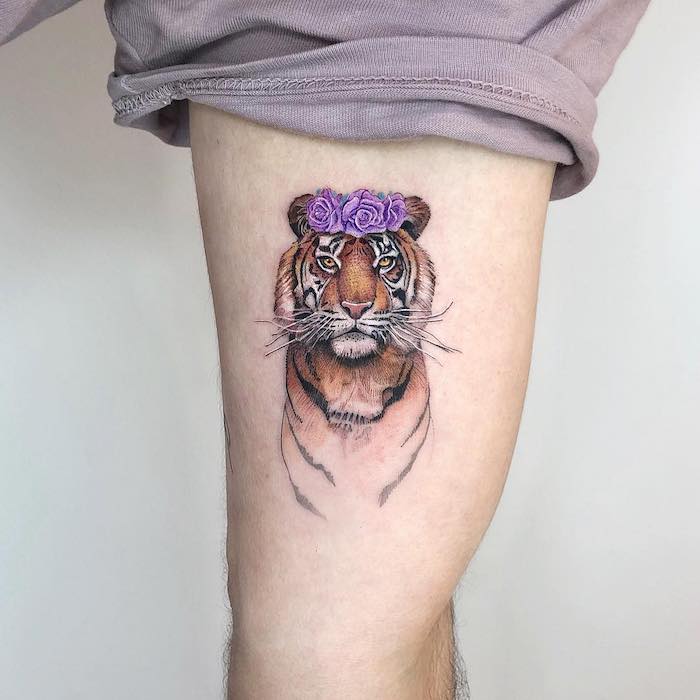 Tiger Tattoo am Bein, farbiges Tattoo am Oberschenkel, Tiger mit lila Rosen auf dem Kopf 