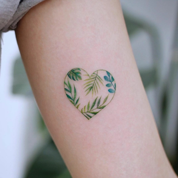 Kleines Herz Tattoo am Oberarm, grünes Herz mit Blättern darin, Frauen Tattoo Ideen 