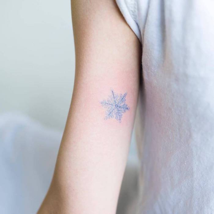 Kleines farbiges Tattoo am Oberarm, blaue Schneeflocke, Mini Tattoo Ideen für Frauen 