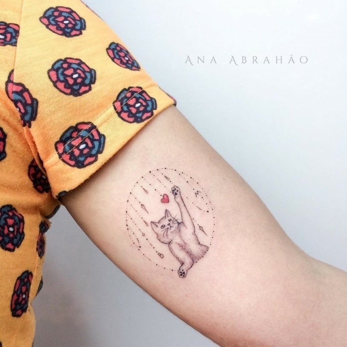 Kleines Tattoo am Oberarm, süßes Katzen Tattoo, Katze und kleines rotes Herz, gelbes Top mit Blumenmuster