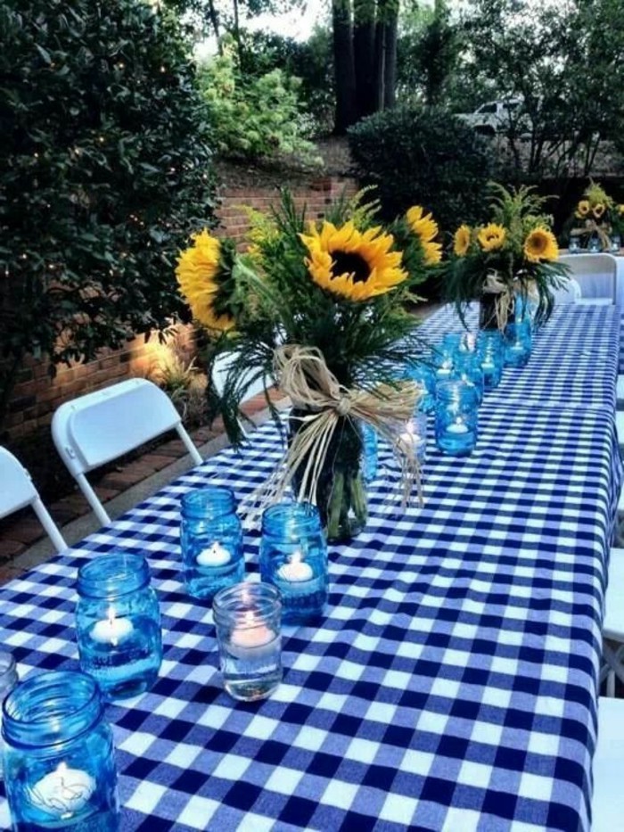 Einfache-Tischdeko-Sonnenblumen-und-Kerzen-in-blauen-Gläsern