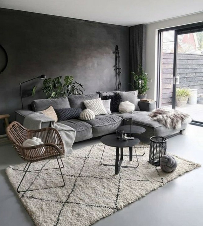 Ecksofa in grau mit Kissen in verschiedene Farben, zwei kleine Tische in schwarz, dunkle Wand, Wohnzimmereinrichtungen
