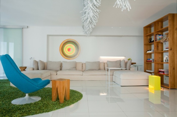 1wandnische-kunst-im-wohnzimmer-blauer-stuhl-gruner-pluschteppich-hocker-aus-holz-glaswand