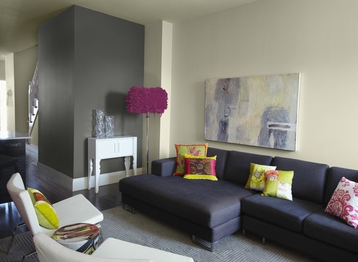 farbgestaltung-waende-grau-leinwand-dunkle-couch-farbige-kissen-plueschteppich-holzboden-dunklem-holz-stehlampe-faedern-weisser-polsterstuhl