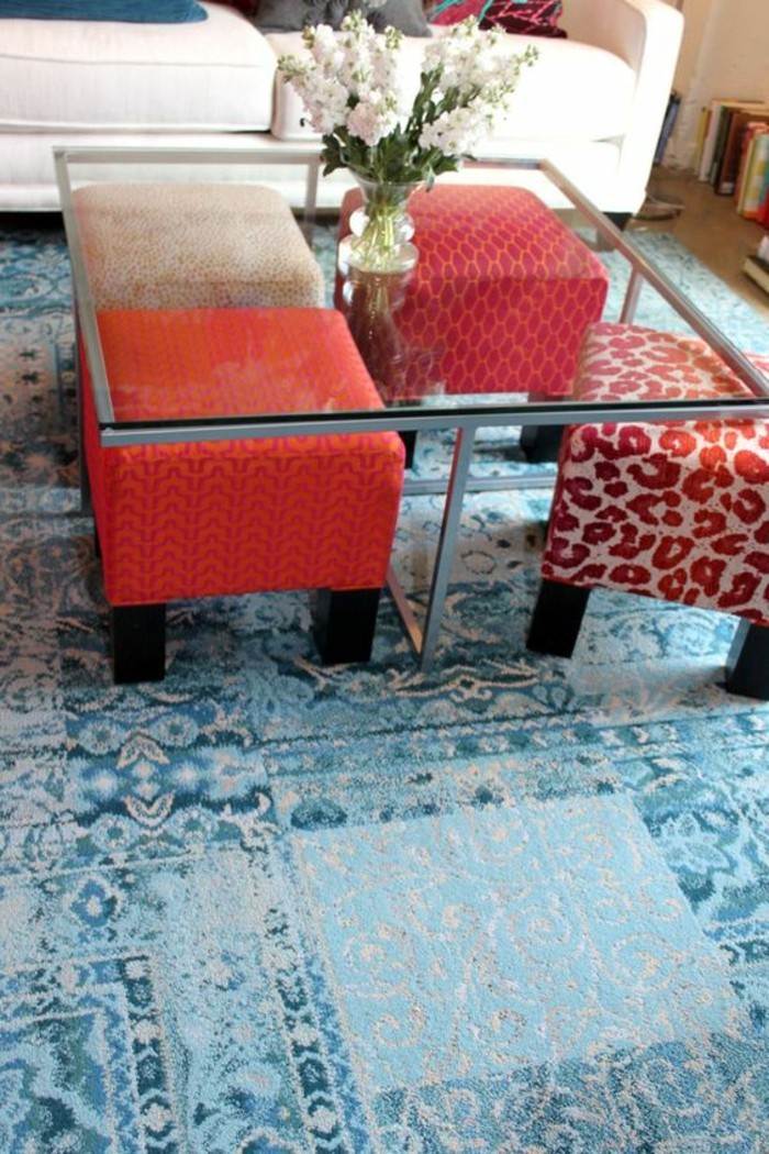 kleines-wohnzimmer-tisch-aus-glas-hocker-blumen-blauer-retro-teppich