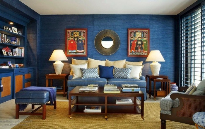 wandfarbe-blau-blaue-couch-blauer-lederhocker-gelber-teppich-buecherregal-eingebaut-jalousien-blau-holztisch-buecher-nachtlampe-sessel-runder-spiegel