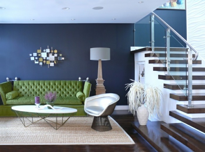 wandfarbe-blau-gruene-polstercouch-teppich-creme-weisser-lederstuhl-dunkler-holzboden-treppen-glasgelaender-stehlampe-dekorative-vase-wanddeko