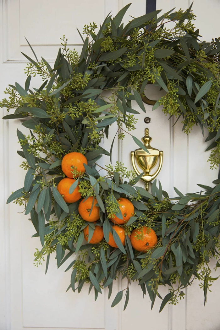 weihnachtskranz tür inspiration grüner kranz dekoriert mit mandarinen weiße eingangstür