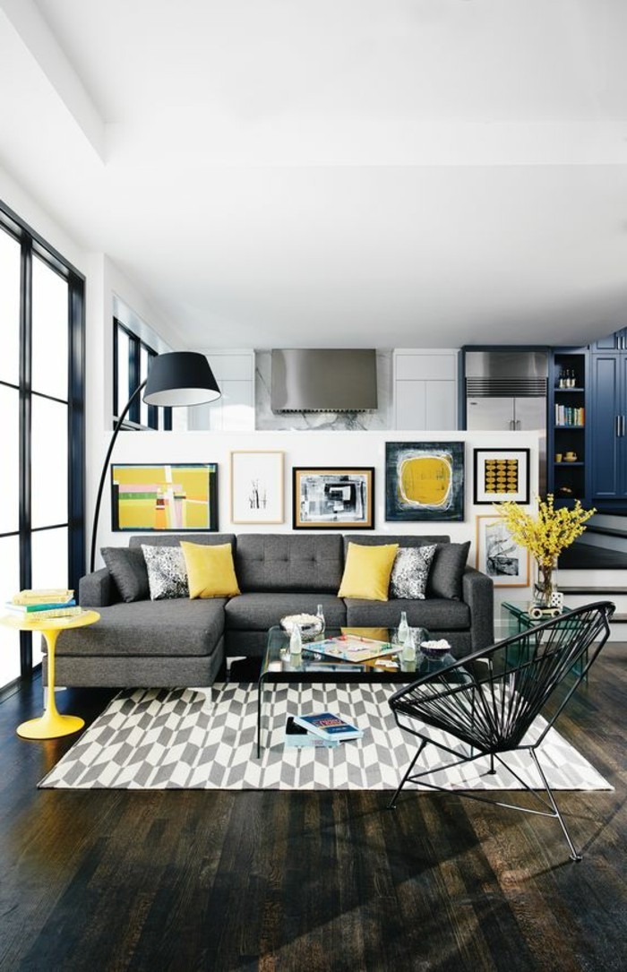 wohnzimmer-farbgestaltung-graue-couch-gelbe-kissen-musteteppich-schwarzer-flechtstuhl-stehlampe-gelber-runder-kaffeetisch-stufen-wohnzimmer-glastisch-schwarzer-holzboden
