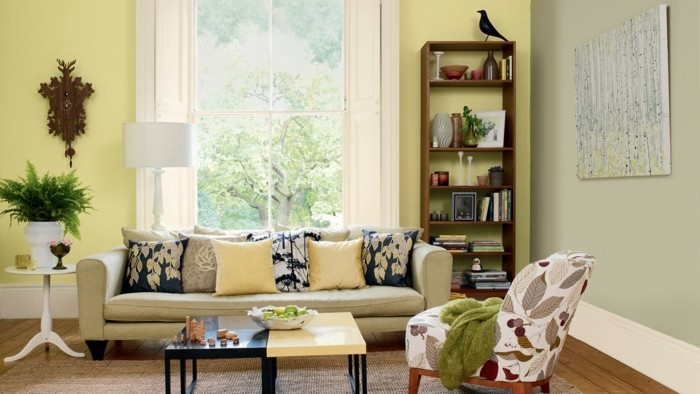 farbgestaltung-wohnzimmer-helle-couch-musterbezuege-kissen-stehlampe-holzboden-teppich-schwarzer-tisch-cremeweisser-tisch-buecherregal-wanddeko-pflanzen