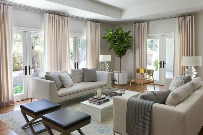farbgestaltung-wohnzimmer-weisse-couch-musterteppich-helle-farben-holzboden-goldener-stuhl-lange-gardinen-lederstuhl-weisser-tisch-mit-buechern-pflanze-in-der-ecke