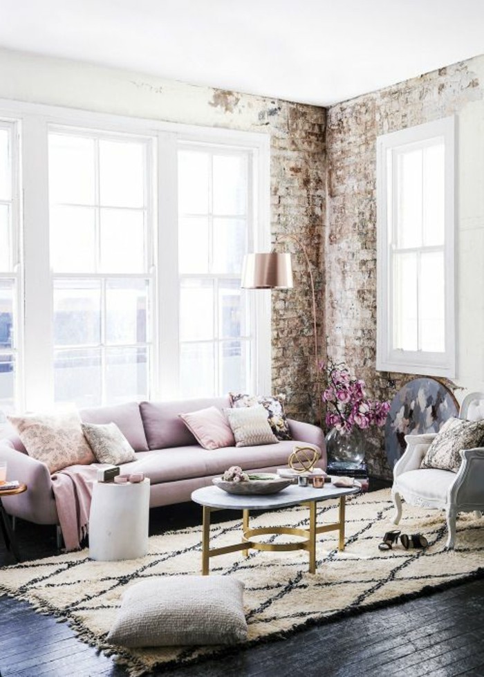 wohnzimmer-vintage-steinwand-rosa-couch-sessel-weiss-ovaler-tisch-musterteppich-schwarzer-boden-stehlampe-farbgestaltung-waende