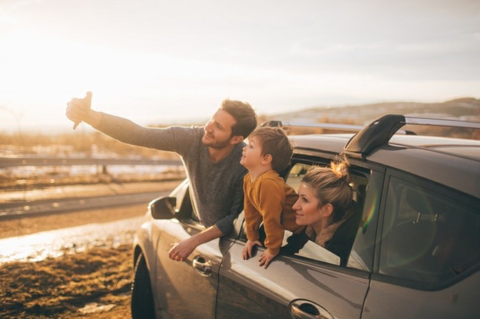 Photo of cute little family posing for the selfie in the nature, during their excursion with family car