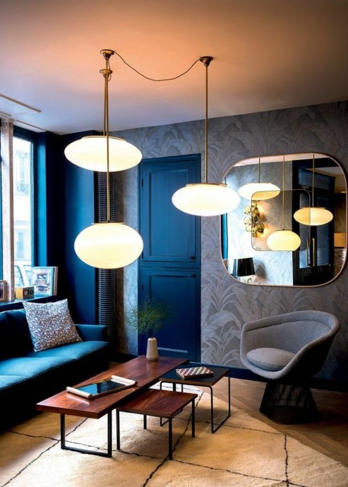 couchtisch-nussbaum-tisch-set-drei-tische-viereckig-dunkles-wohnzimmer-blaue-waende-weisser-plueschteppich-spiegel-indirektes-licht