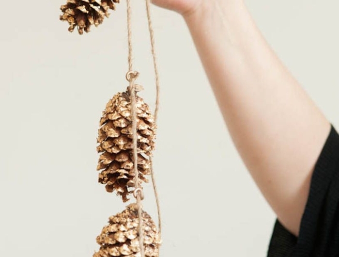 dekoration mit zapfen weihnachten basteln winter inspiration hand hält tannenzapfen girlande weihnachtsdekoration