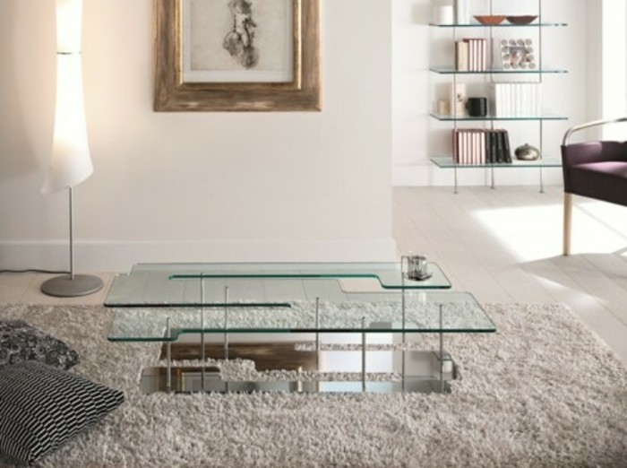 eleganter-designer-couchtische-aus-glas-und-metall-mit-vielen-faechern-wohnzimmer-mit-plueschteppich-weisse-waende-indirektes-licht