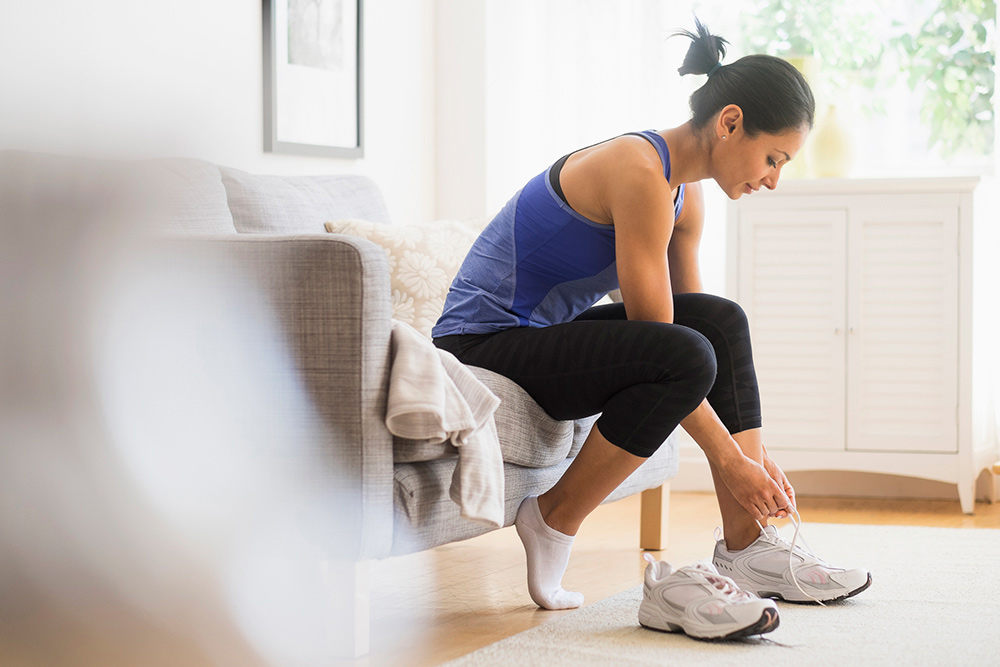 woman ties workout shoes home