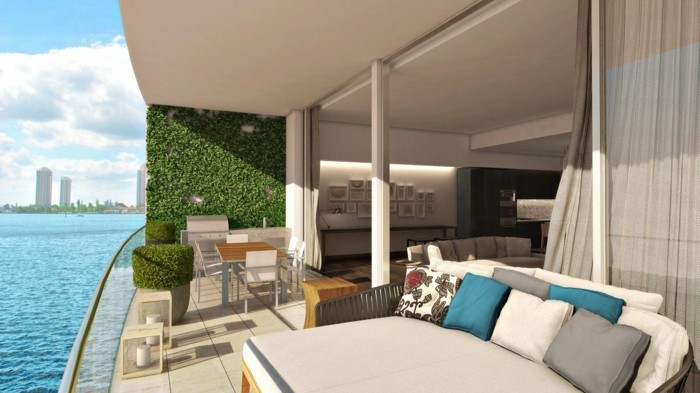 1-balkon-ideen-grüne-pflanzen-meer-tisch-stühle-kissen-großer-sofa-fliesen-modern