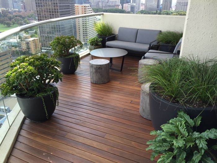 4-balkon-ideen-grauer-sofa-tisch-grüne-pflanzen-schwarze-blumentöpfe-boden-aus-holz-holzpaletten