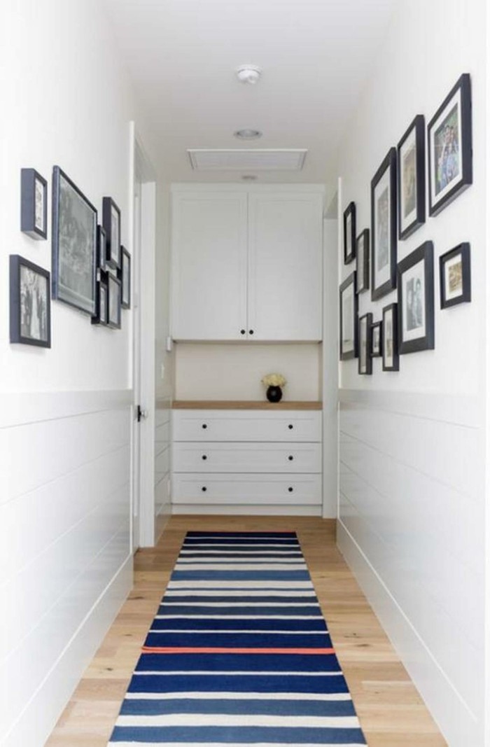 Langer-flur-deko-teppich-auf-streifen-und-bilder-an-den-wänden-regal-im-hintergrund