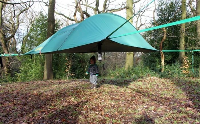 ein-grünes-campingzelt-im-wald-und-ein-kind