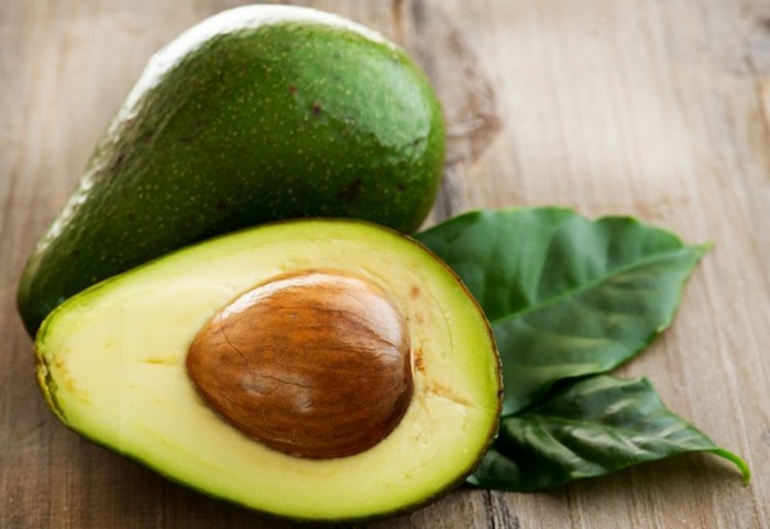gesichtsmaske-selber-machen-avocado-grüne-blätter-hölzerner-tisch-gesundheit-pflege