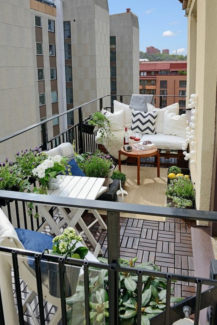 ideen-kleiner-balkon-boden-aus-holz-holzfliesen-sofa-runder-tisch-blumen-teppich-pflanzen