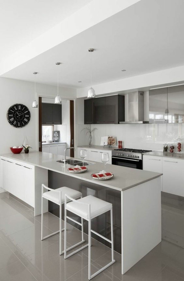küchendekoration-schwarze-wanduhr-weiße-stühle-ofen-lampen-aspirator-schränke-kücheninsel
