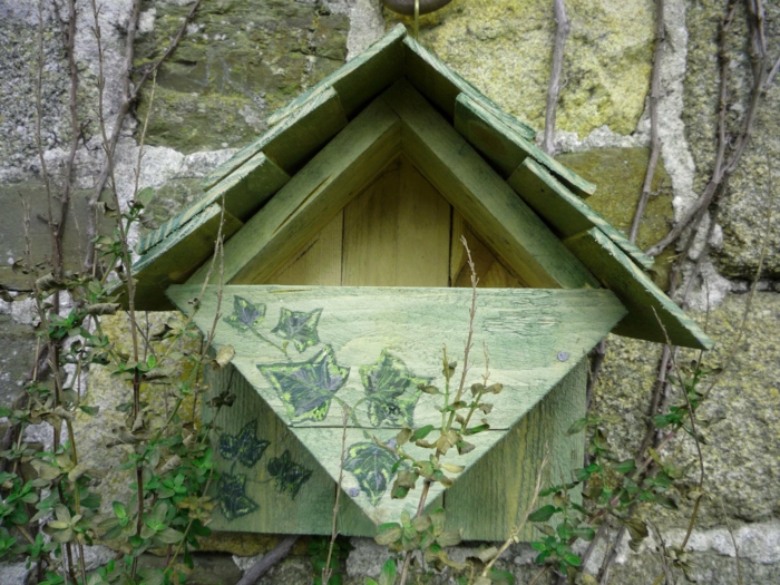 grünes Holzhäuschen für Vögel, montiert an Natursteinmauer
