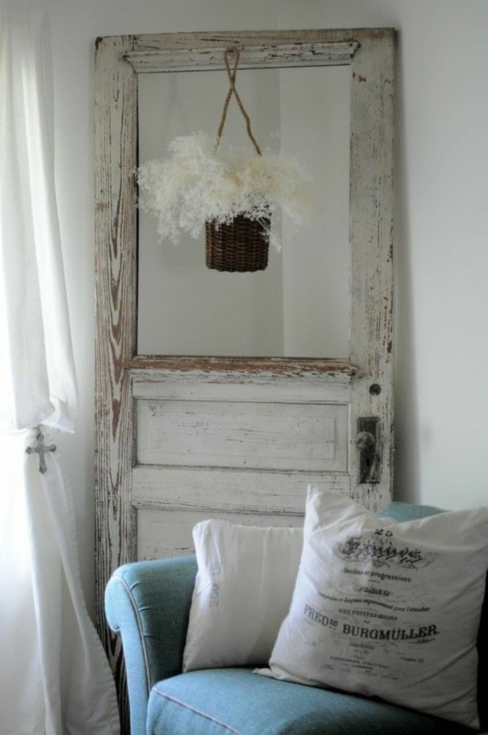 Alte-tür-deko-in-weißer-farbe-mit-hängenden-blumentopf-hinter-blaues-sofa
