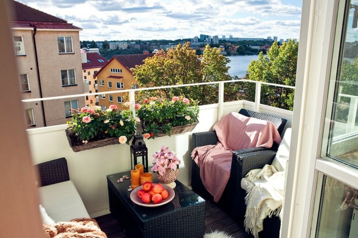 balkon-deko-flechtmöbel-schwarz-weiße-schlafdecke-pinke-schlafdecke-obst-kerzen-pflanzen-blumen-holzboden
