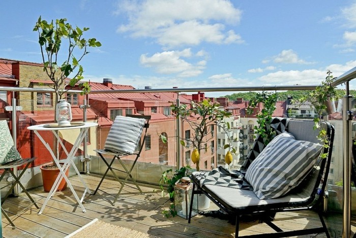 balkongestaltung-mediterran-holzboden-metallstühle-kissen-glasgeländer-weißer-rundtisch-zitronenbaum