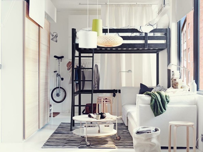 einzimmerwohnung-einrichten-wohnzimmer-hochbett-musterteppich-weiße-couch-weißer-rundtisch-holzhocker-kleiderschrank