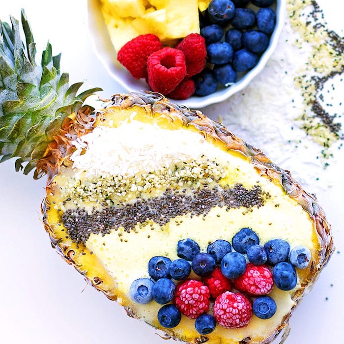 Smoothie in Ananas, mit gefrorenen Blaubeeren und Himbeeren dekoriert, schnelles Rezept für den Sommer 