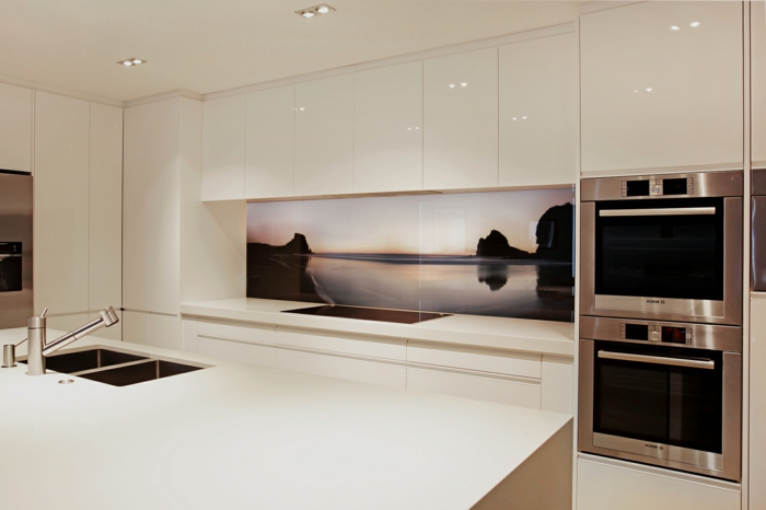 weiße küche mit großer kücheninsel und interessanter küchenrückwand 