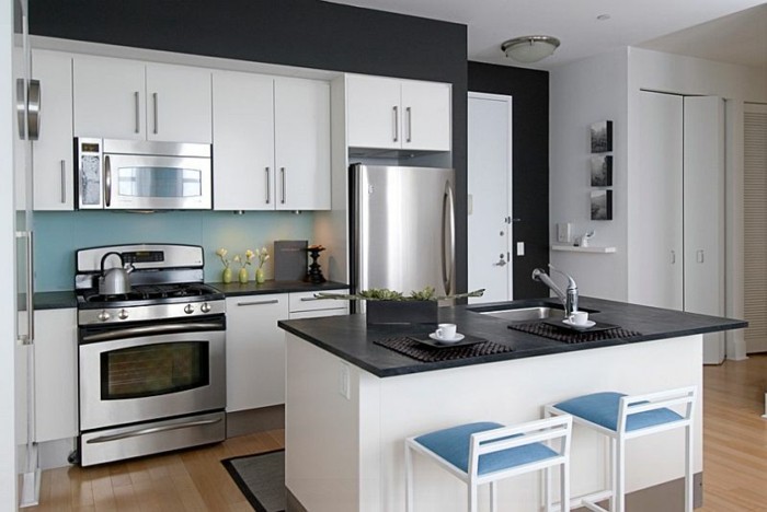 küche-schwarze-wände-parkettboden-kochinsel-blaue-stühle-weiße-küchenschranktüren
