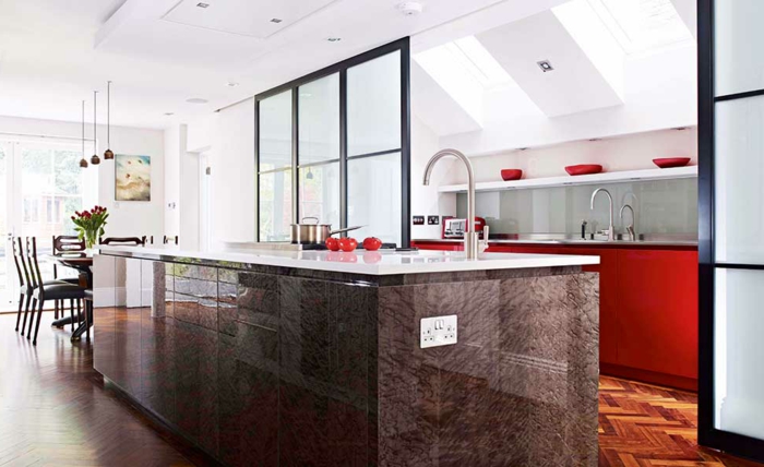 offene-küche-mit-theke-glastrennung-parkettboden-rote-küchenfronten-rote-schüssel-esszimmertisch-blumen