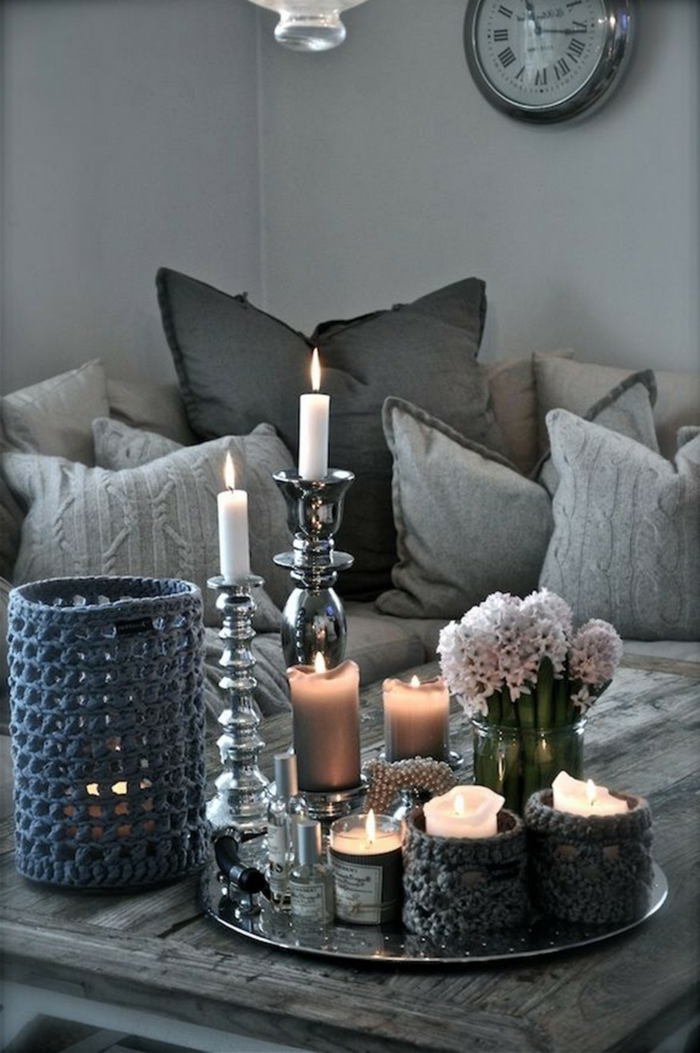 wunderschöne Wohnzimmer Deko Ideen für Couchtisch mit Kerzen in unterschiedlicher Größe und weißen Blumen