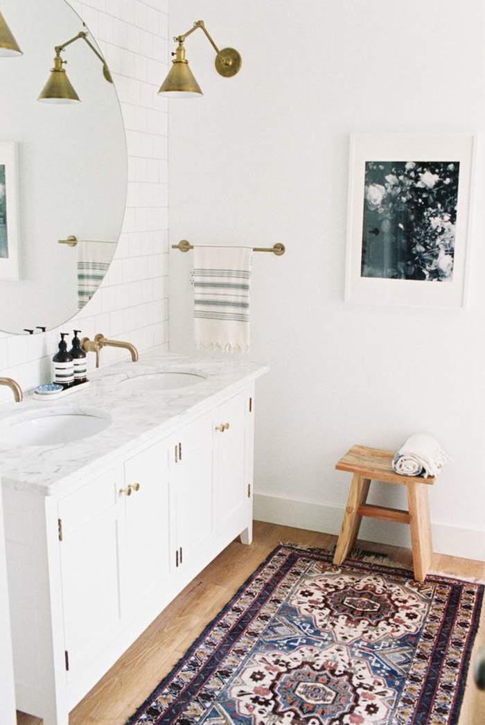 minimalistisches Badezimmer mit rundem Spiegel mit einfachem Rahmen, kleiner Holzstuhl, Musterteppich