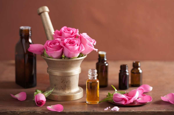Kosmetik selber machen: Rosenöl in Kosmetikflaschen aus dunklem Glas, Rosenblättern, Rosen, Mörser