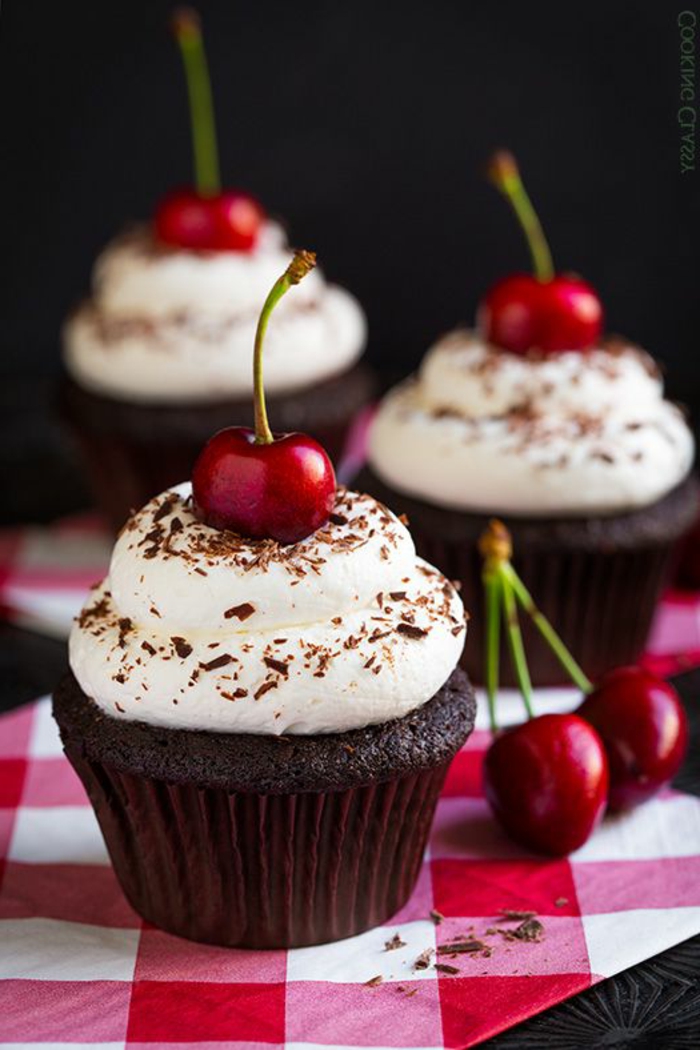 schoko-cupcake mit weißer sahne, kirschen und schokolade dekorieren