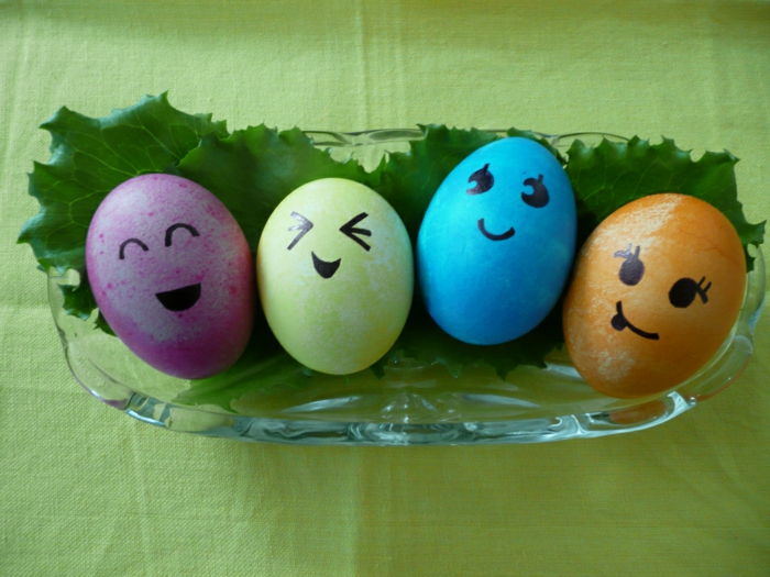 Ostereier Gesichter in vier verschiedenen Farbe in einer Schale mit Blätter