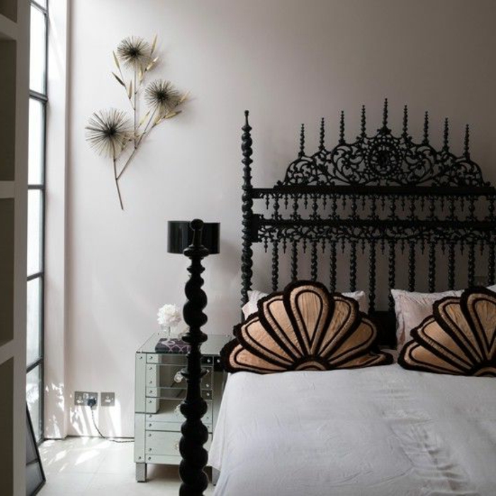 gotisch eingerichtetes Schlafzimmer mit Doppelbett aus Metall mit vielen Ornamenten, Musterkissen, Wanddeko