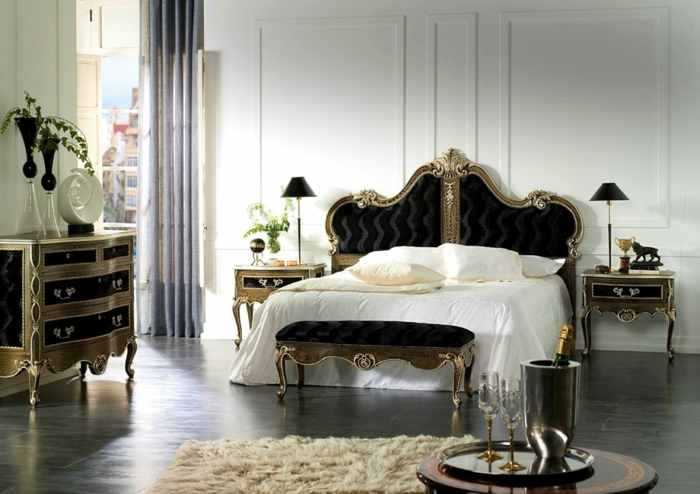 großes Schlafzimmer mit Doppelbett im gotischen Stil, Gothic-Kommode in Schwarz und Gold, cremeweißer Teppich